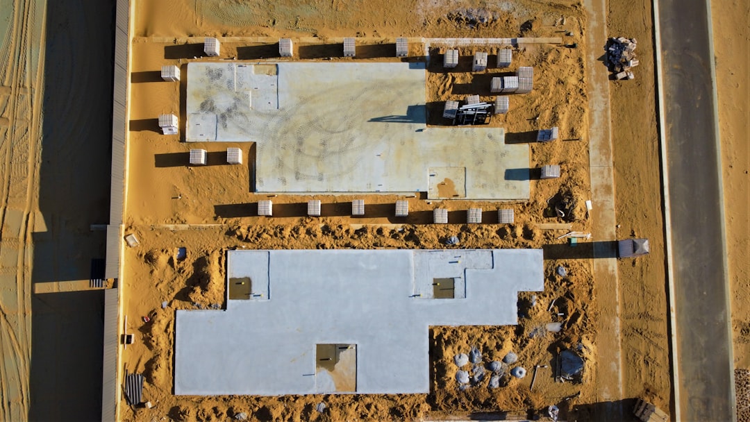 A contractor grading a house pad with heavy equipment and stakes showing elevations